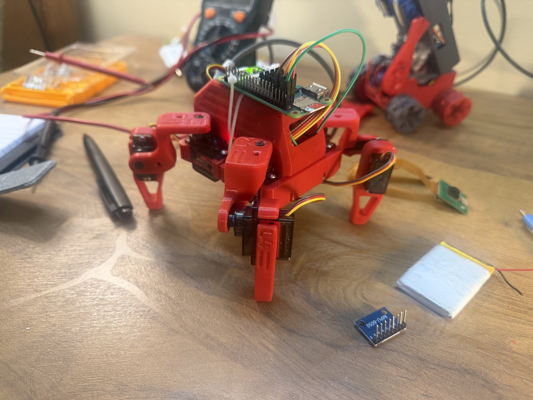Molty, a red four-legged robot pet prototype, standing on a workbench